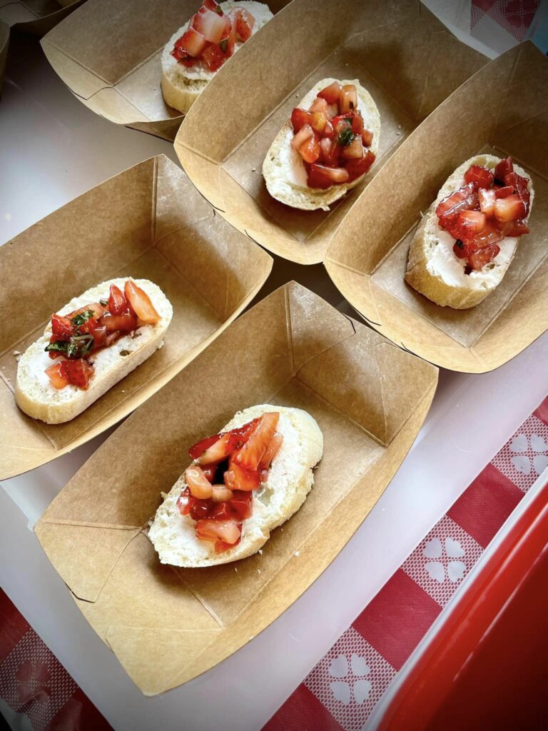 Paper plates with strawberry bruschetta samples.